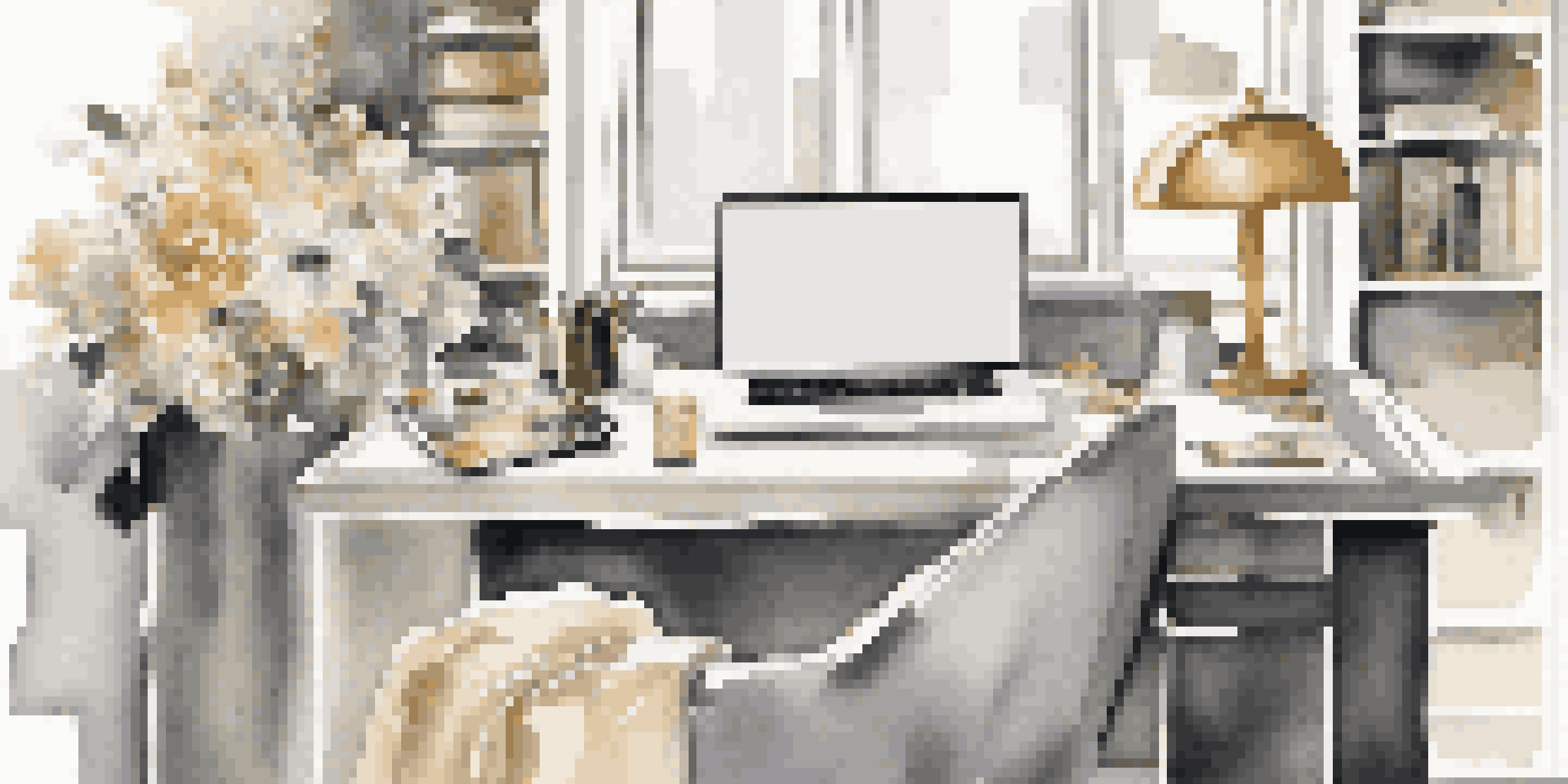 A fashion editor's stylish workspace with magazines, a laptop, fabric swatches, and flowers, illuminated by natural light.
