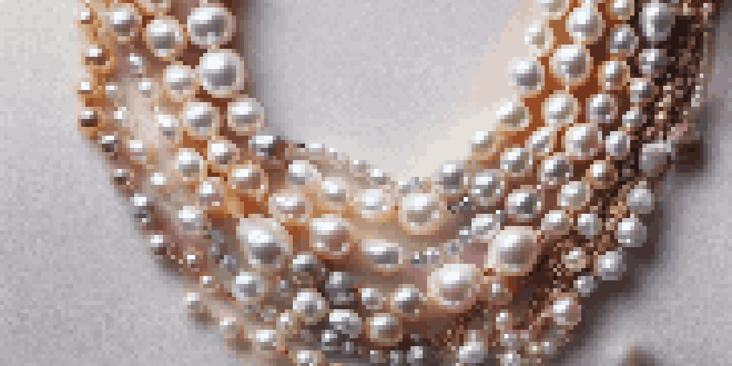 A close-up of a pearl necklace showcasing a mix of classic and dyed baroque pearls on a velvet fabric background.