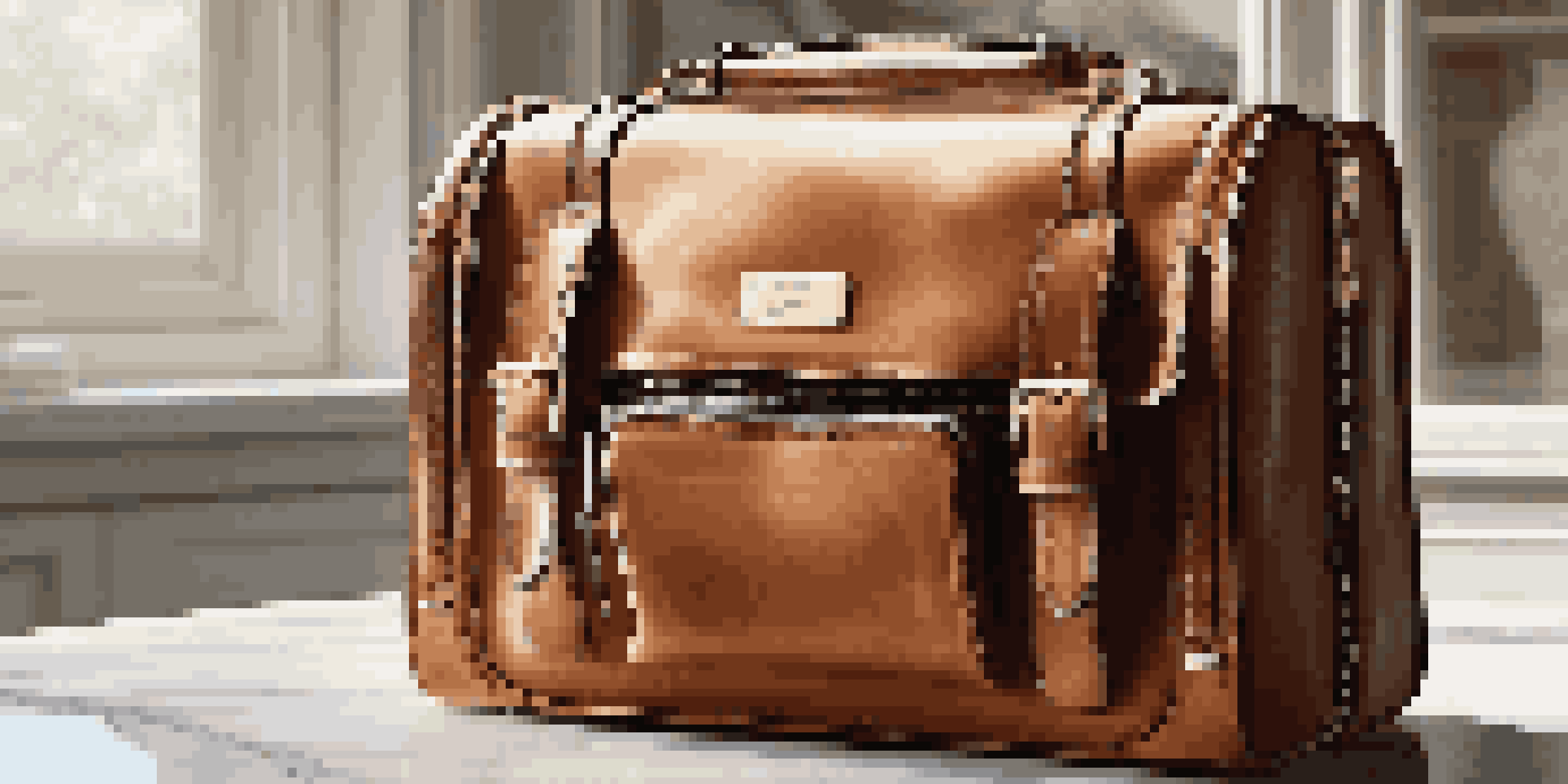 A luxury leather travel bag open on a marble countertop, displaying organized travel essentials inside.