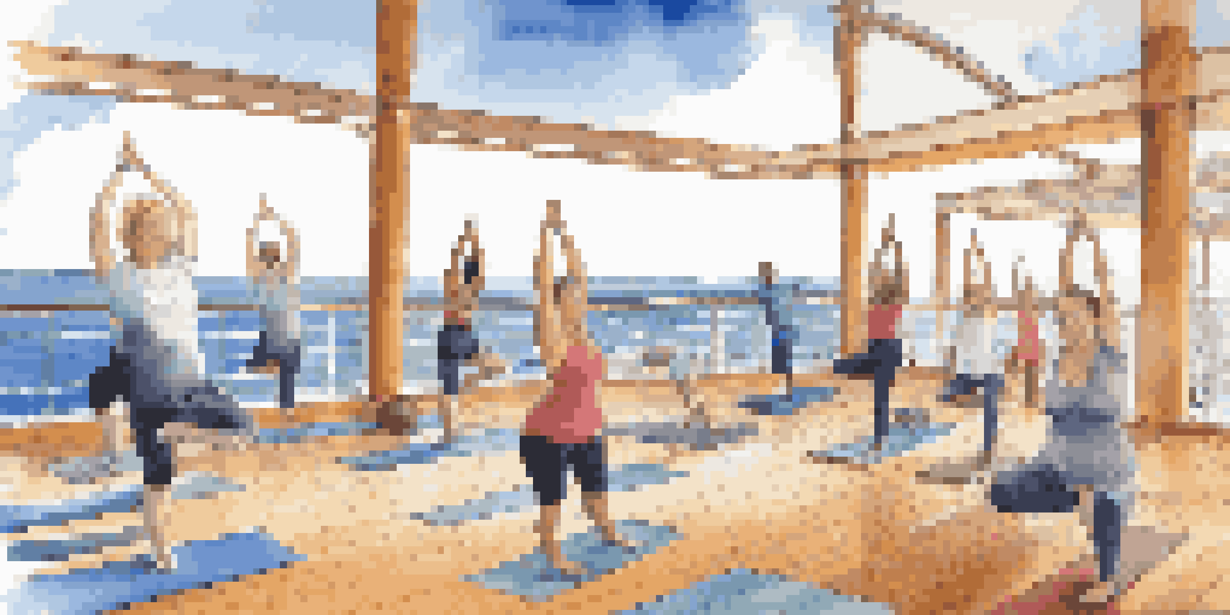 A yoga class on a cruise ship deck with participants practicing poses against a beautiful ocean backdrop.