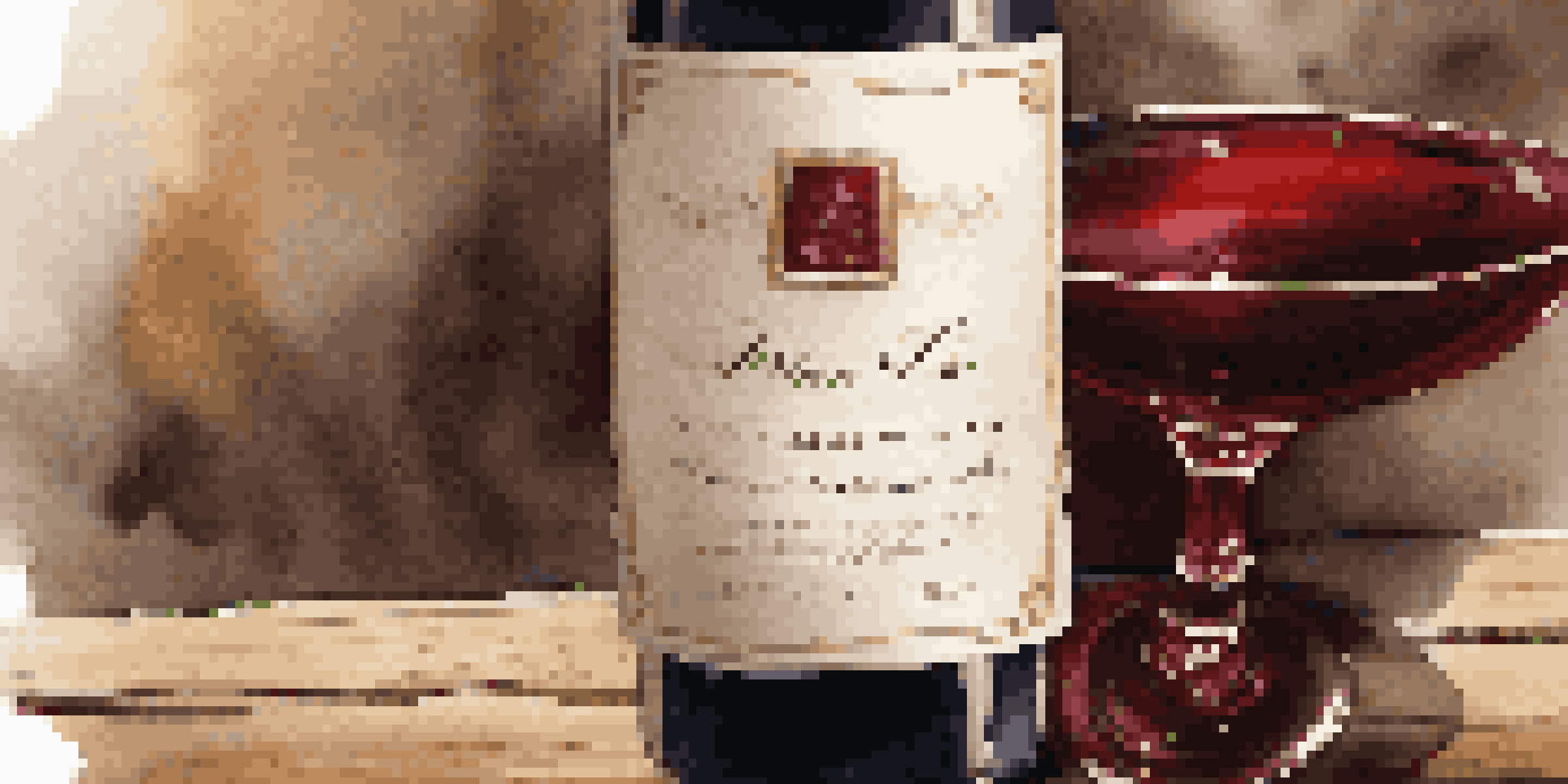 A luxury wine bottle with a decorative label on a wooden table, accompanied by a glass of red wine, illuminated by soft lighting.