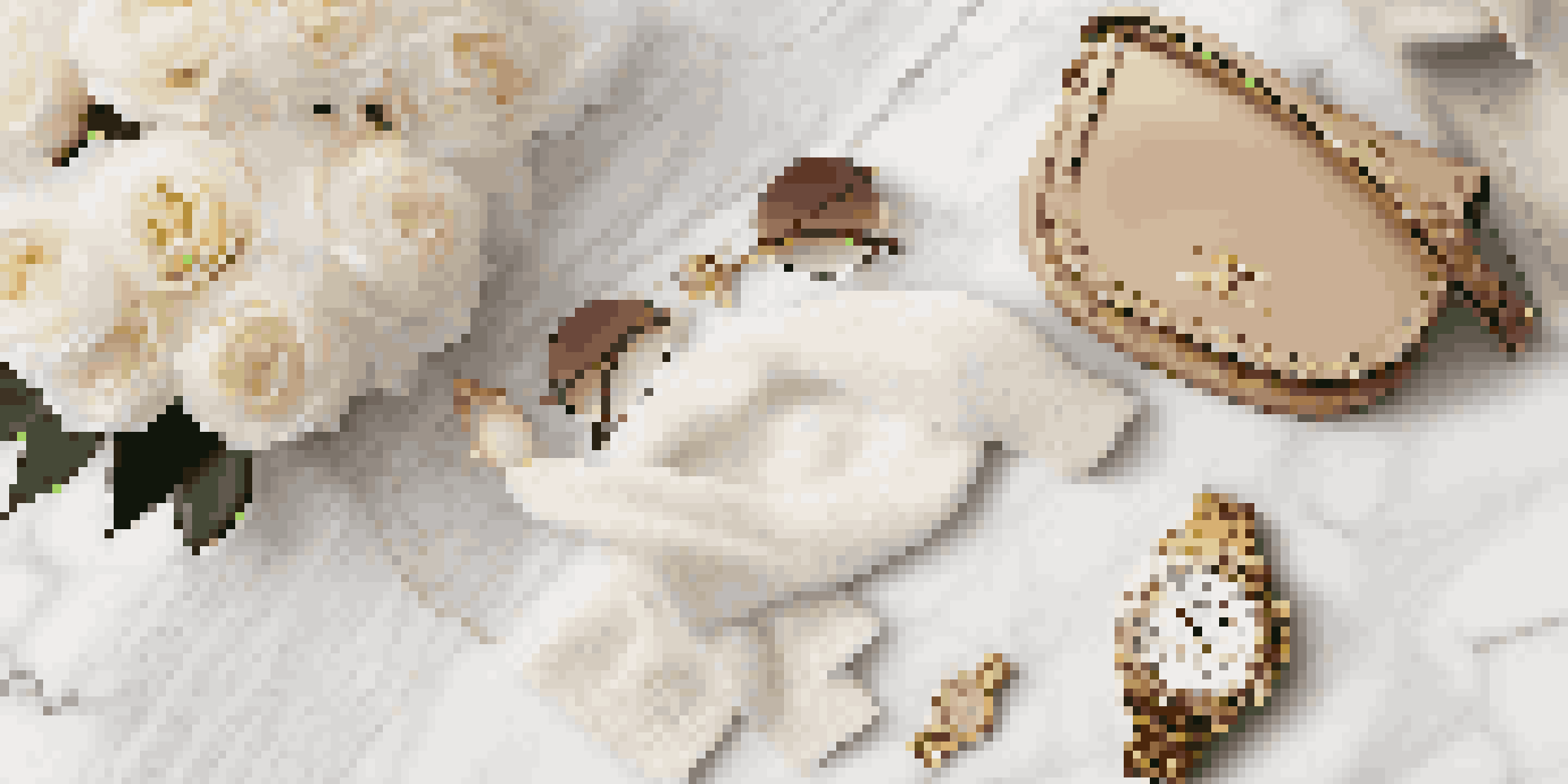 A flat lay of a designer handbag, sunglasses, and a gold watch on a marble surface, with white flowers and a cashmere scarf, illuminated by warm natural light.