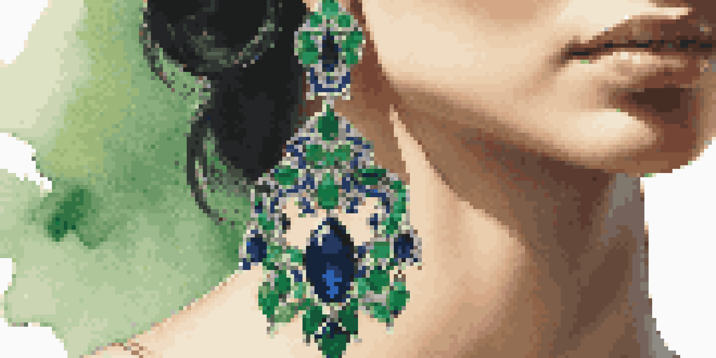 A detailed close-up of a luxurious emerald green and sapphire blue statement earring with intricate floral designs, set against a softly lit background.