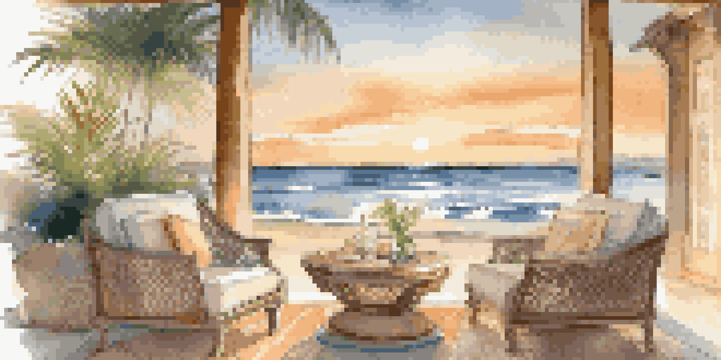 A couple engaged in a heartfelt conversation on a beachfront retreat, surrounded by elegant seating and a sunset backdrop.