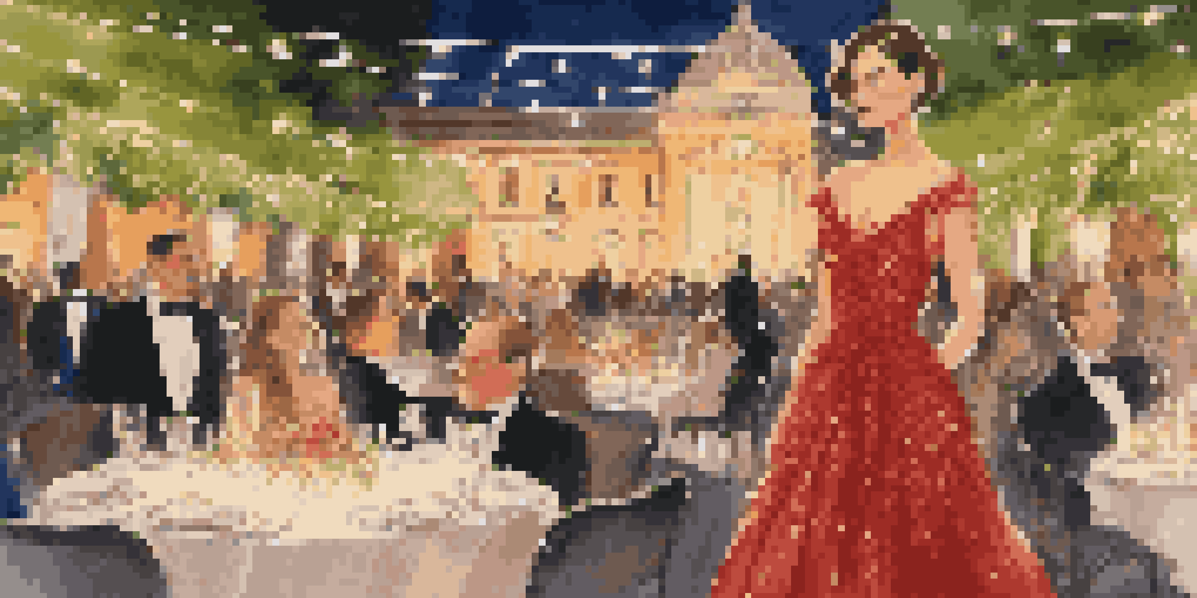 A woman in a red evening gown at an outdoor gala surrounded by fairy lights and beautiful decorations.