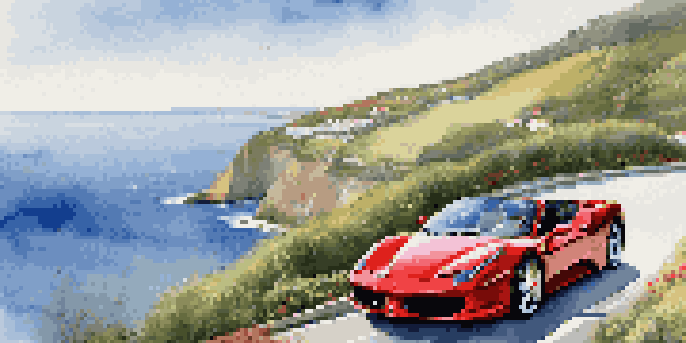 A red Ferrari parked on a coastal road with cliffs and ocean in the background, under a bright blue sky.