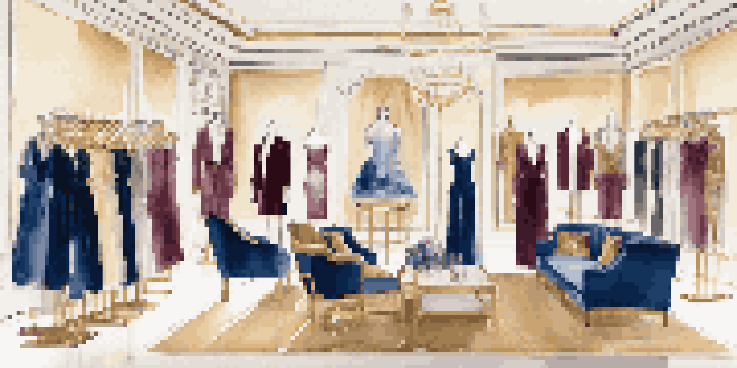 A luxury fashion rental showroom with elegant clothing displays, framed fashion photography on the walls, and plush seating areas in a warm, inviting atmosphere.