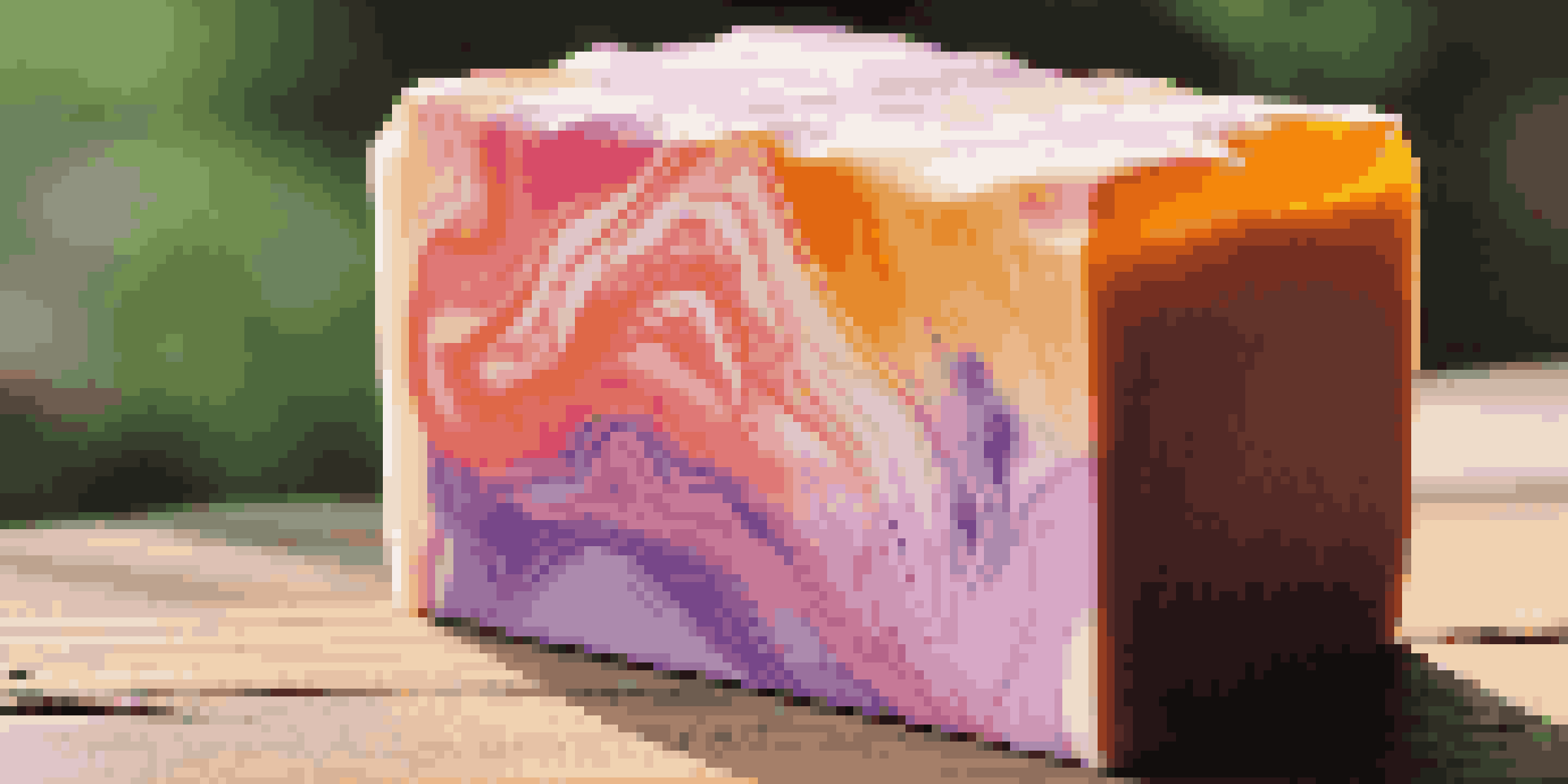 A close-up of a colorful artisanal soap bar with marbled sunset colors on a wooden surface.