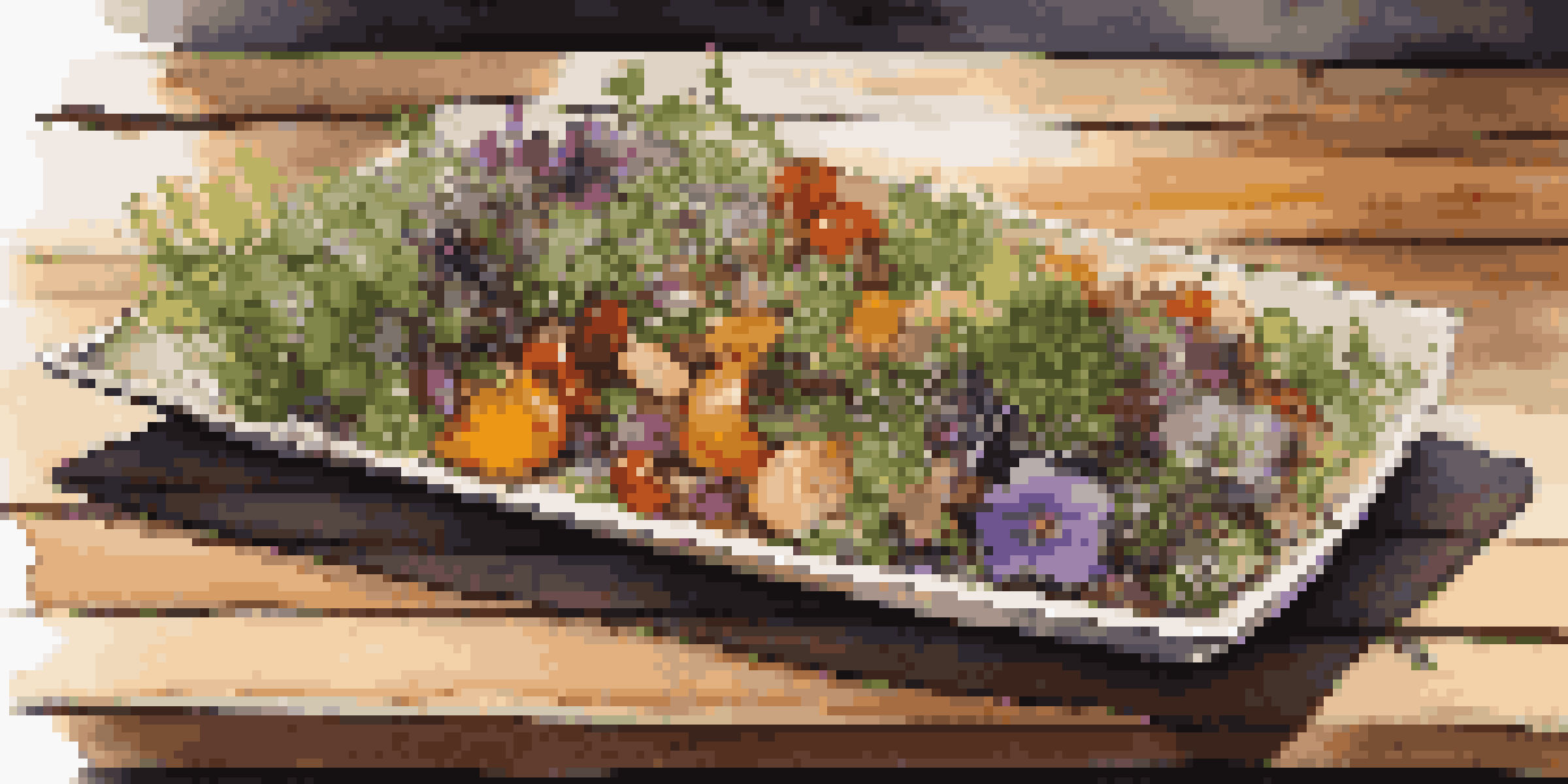 A vibrant vegan dish with seasonal vegetables and edible flowers, presented on a wooden table in a stylish restaurant.