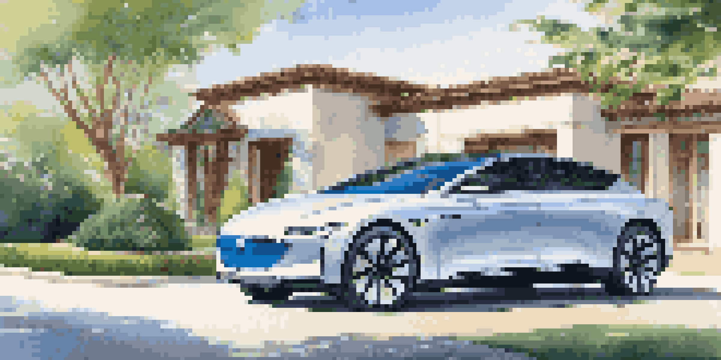 A luxury electric vehicle parked in front of a modern mansion, surrounded by greenery, with sunlight reflecting off its glossy surface.