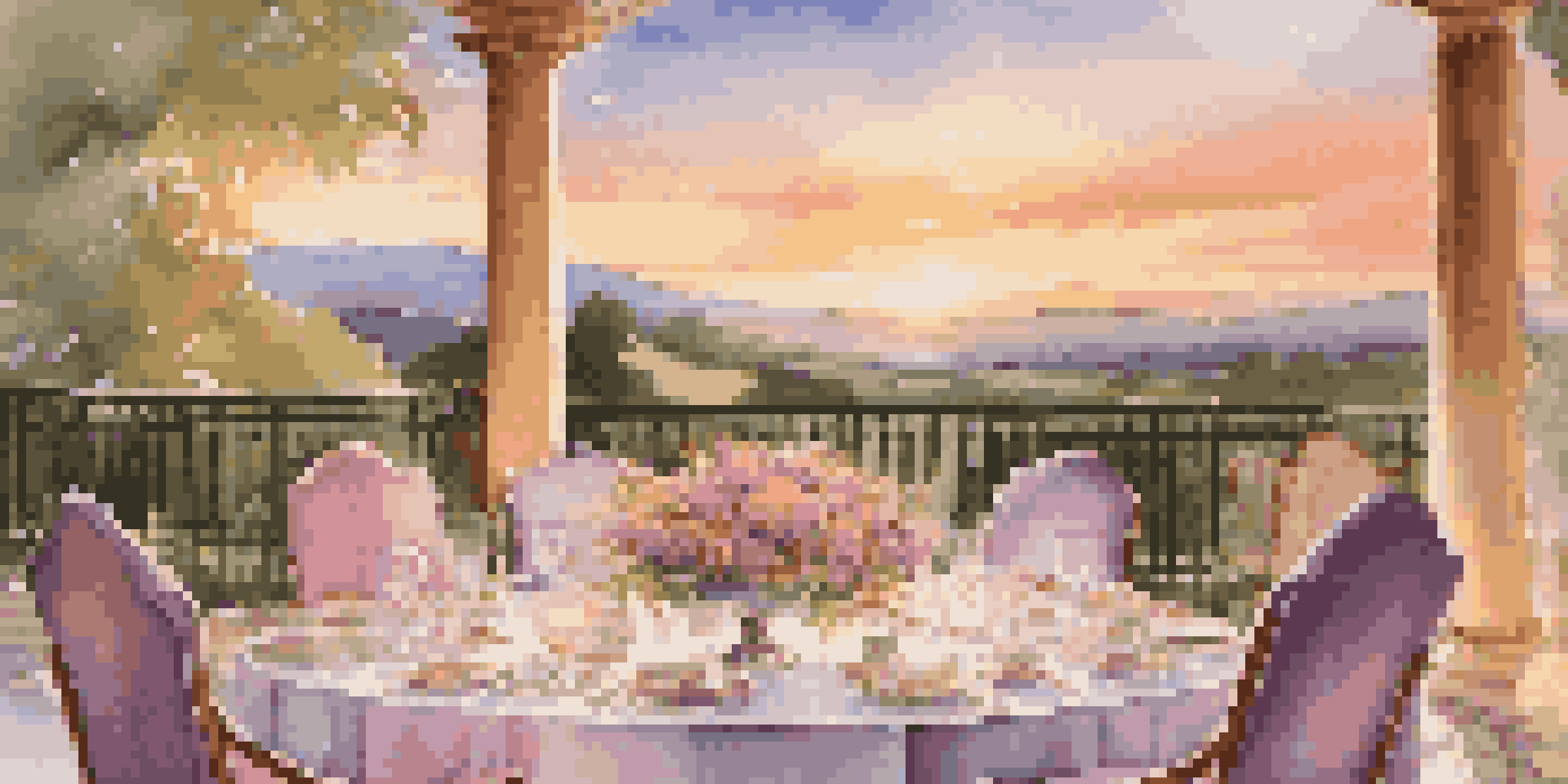 A beautiful outdoor dining setup overlooking a scenic view during sunset, with a well-set table and floral decorations.