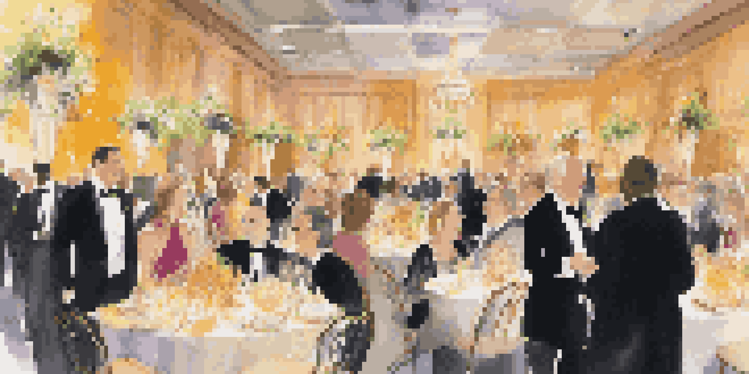 An upscale charity gala with elegantly dressed attendees, floral decorations, and an auction table.