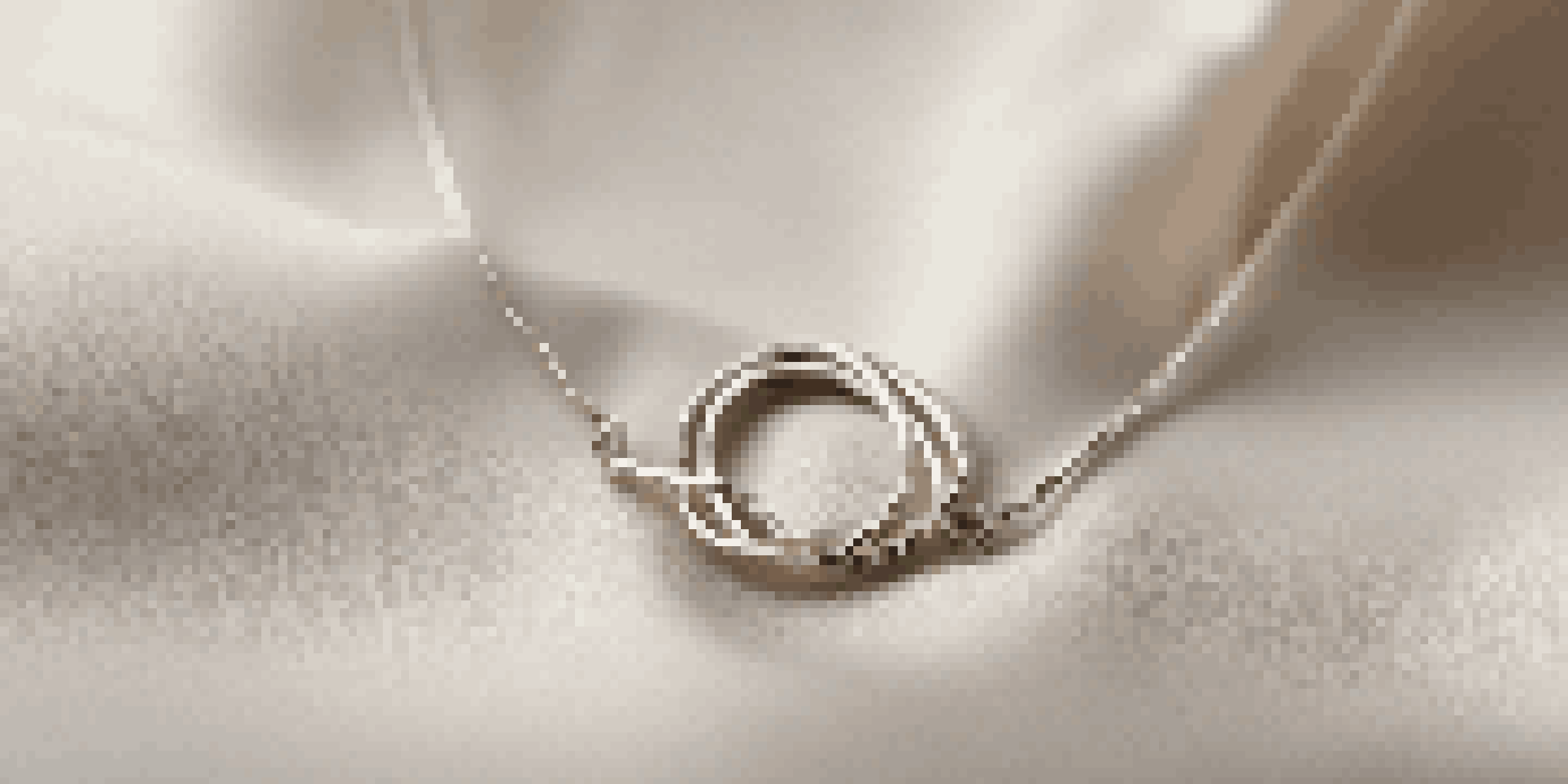 Close-up of a delicate minimalist necklace made from recycled silver, displayed on a soft velvet cloth with warm natural light.