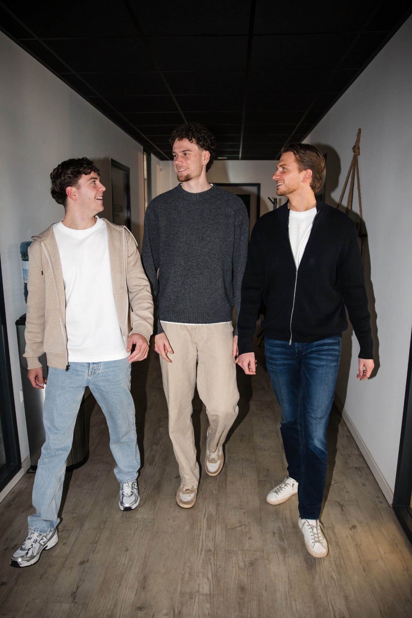 Drie collega's lopen samen door de gang op kantoor