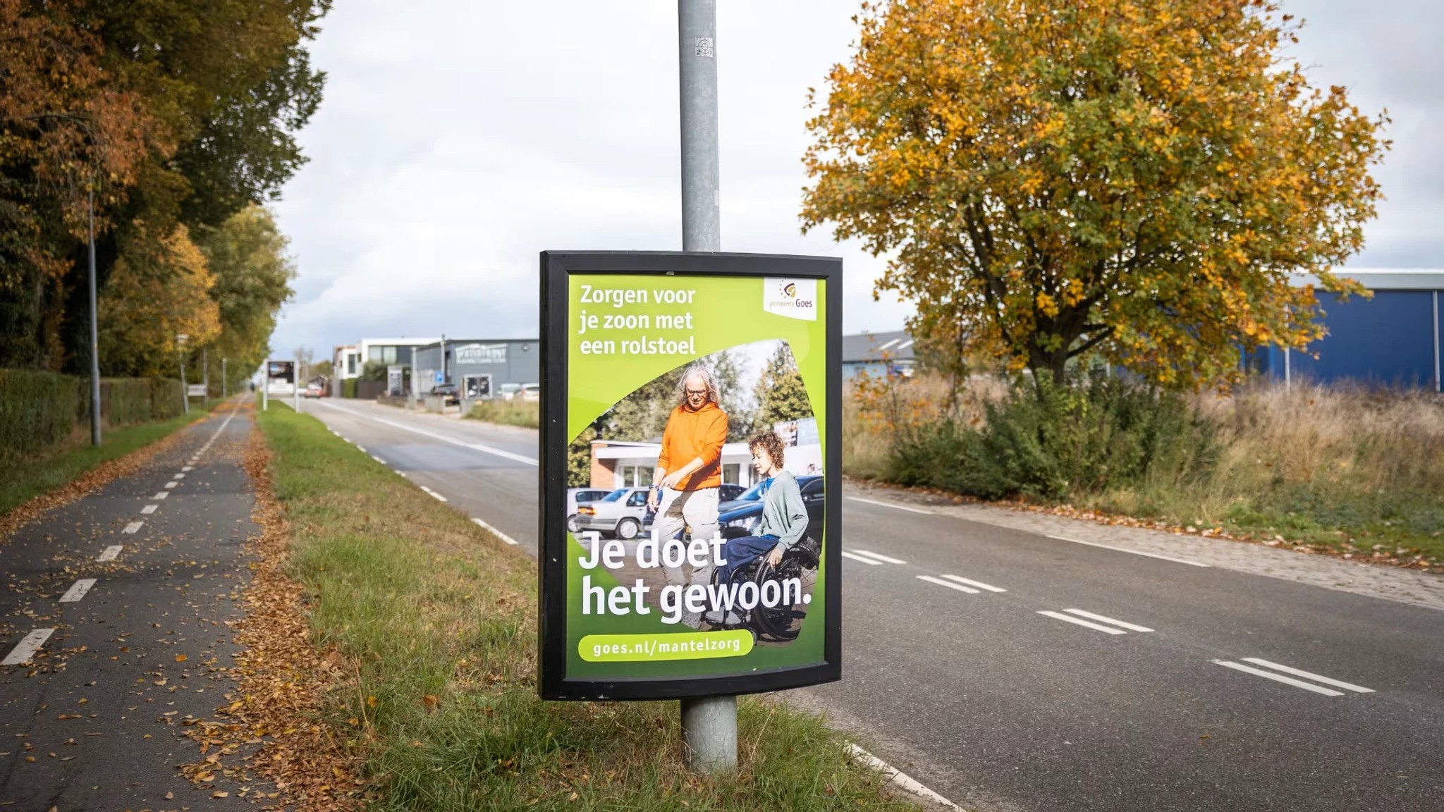 Campagnebord Je doet het gewoon over zorgen voor je zoon met een rolstoel, langs een fietspad