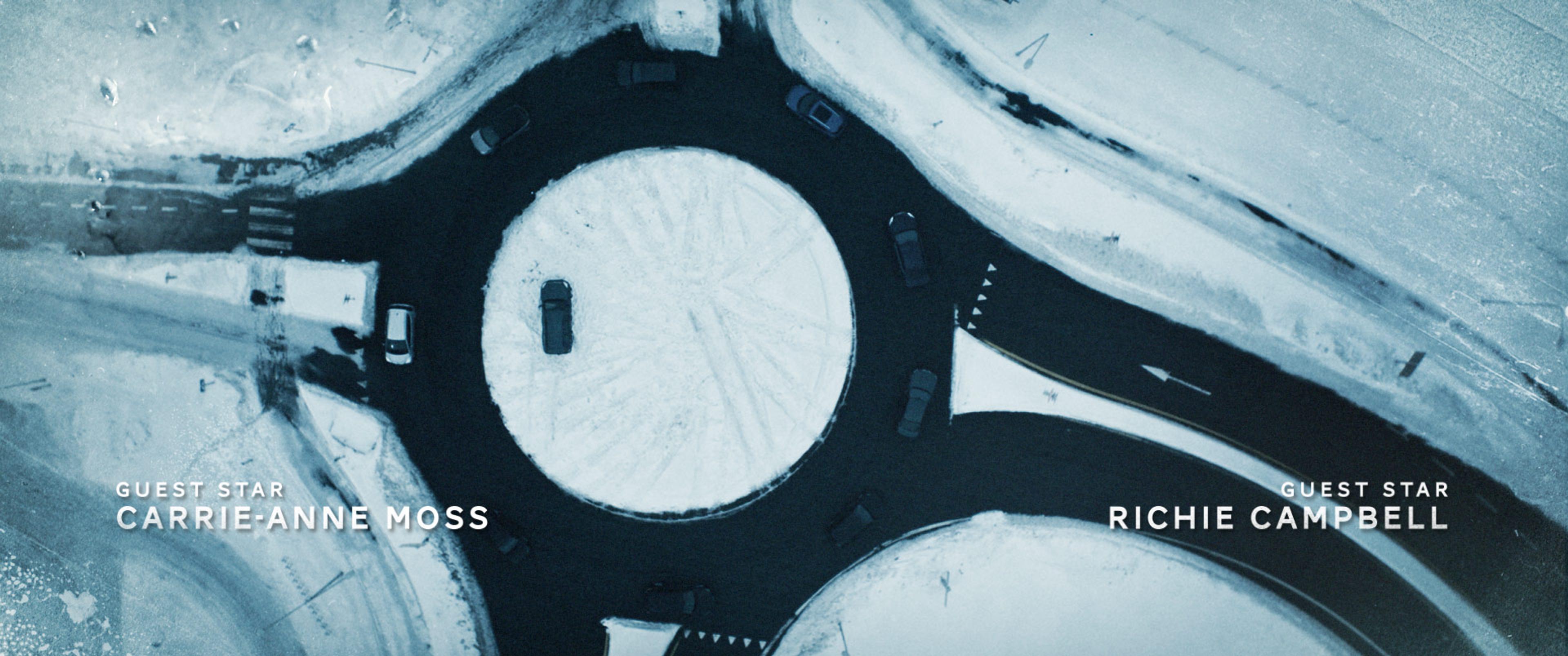 roundabout in snowy weather filmed from drone with credits overlay