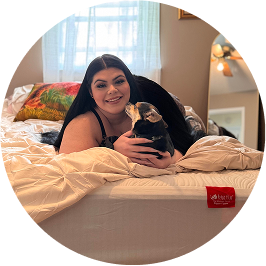 Woman getting kisses from her Chihuahua on a mattress covered by a Big Fig mattress protector