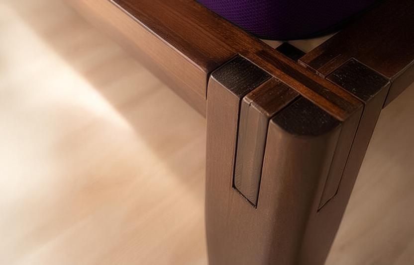 Close-up of a wooden platform bed leg with Japanese-style joint on a light wood floor.