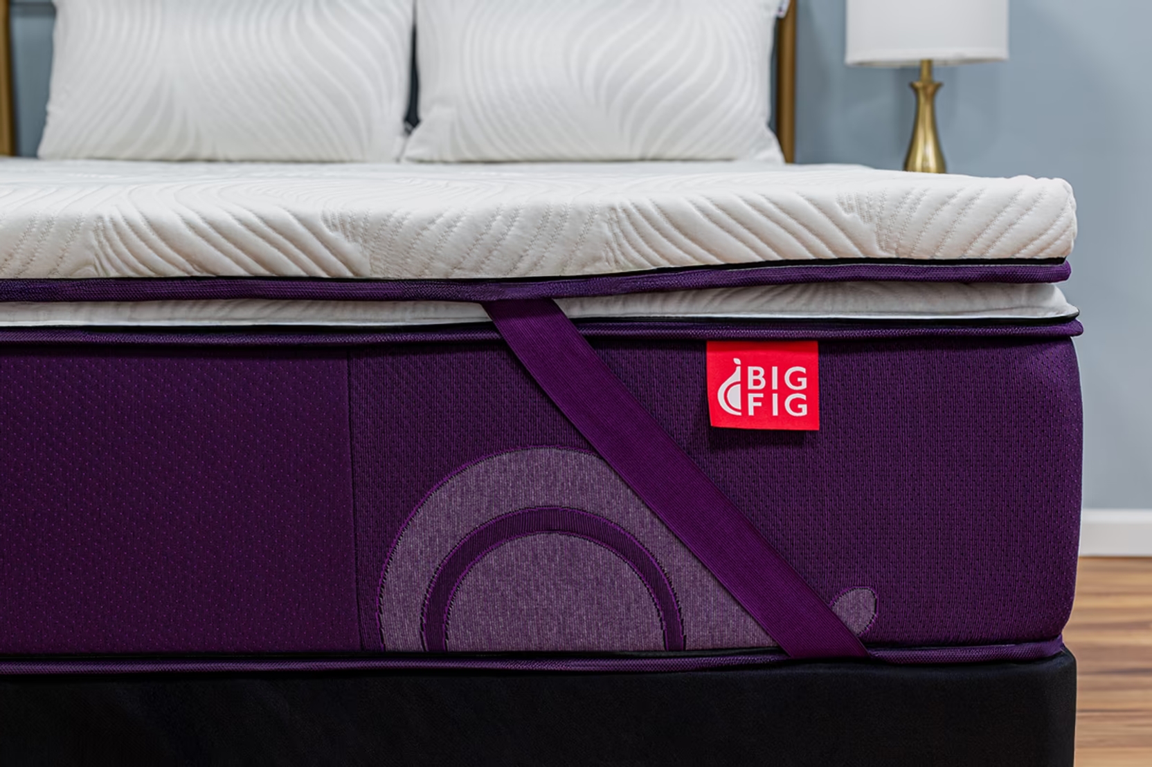 Big Fig Micro-Coil Topper with white, quilted surface attached to a Big Fig Classic mattress, using deep fig colored corner straps for added support.