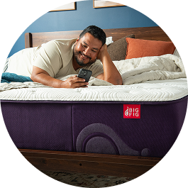 Man with short black hair and facial hair looking at phone on a Big Fig mattress