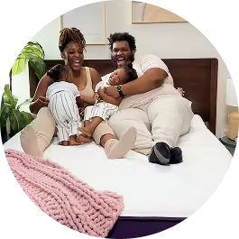 Black family with small children smiling and laughing in bed.