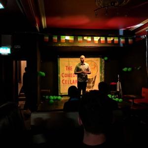 Matt in Ireland. A picture of him on Stage at comedy cellar, and in front of the Cliffs of Mohr