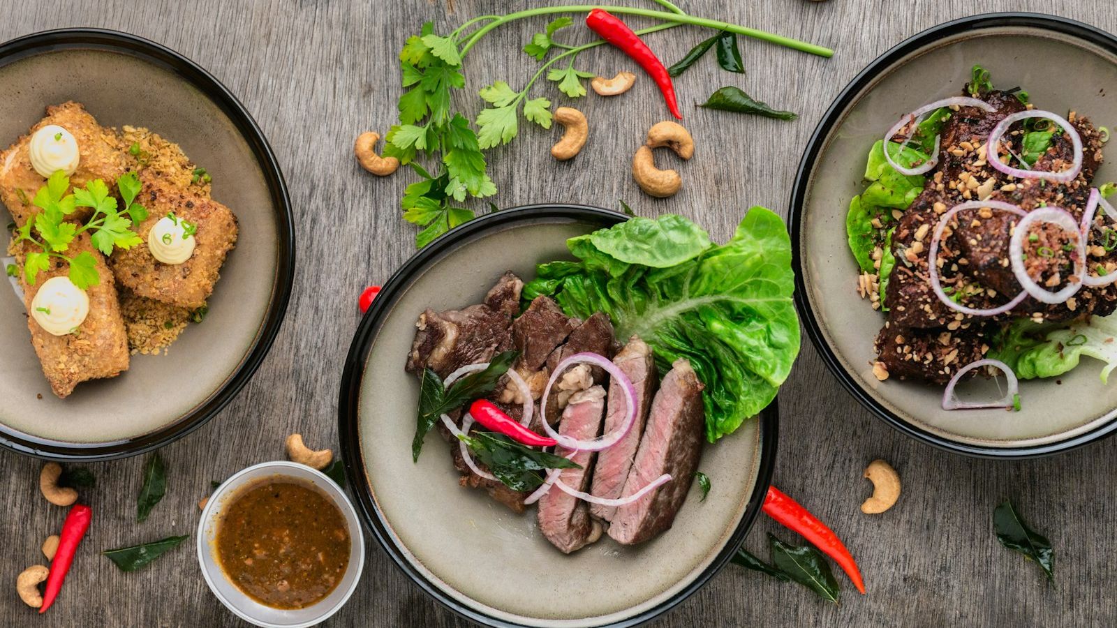 three plates of asian food on wood table