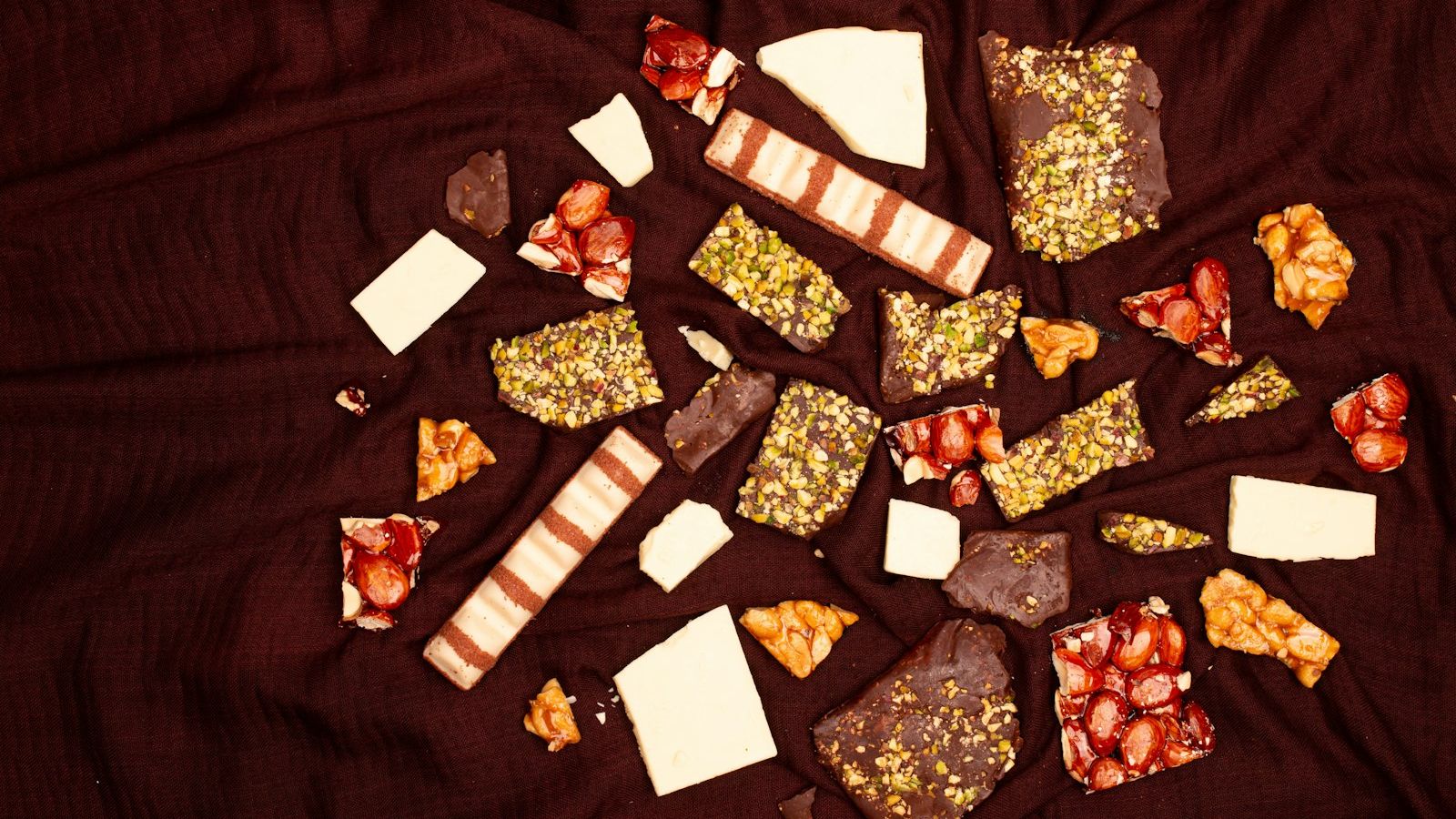 Assortment of broken chocolate bars and sweets on fabric