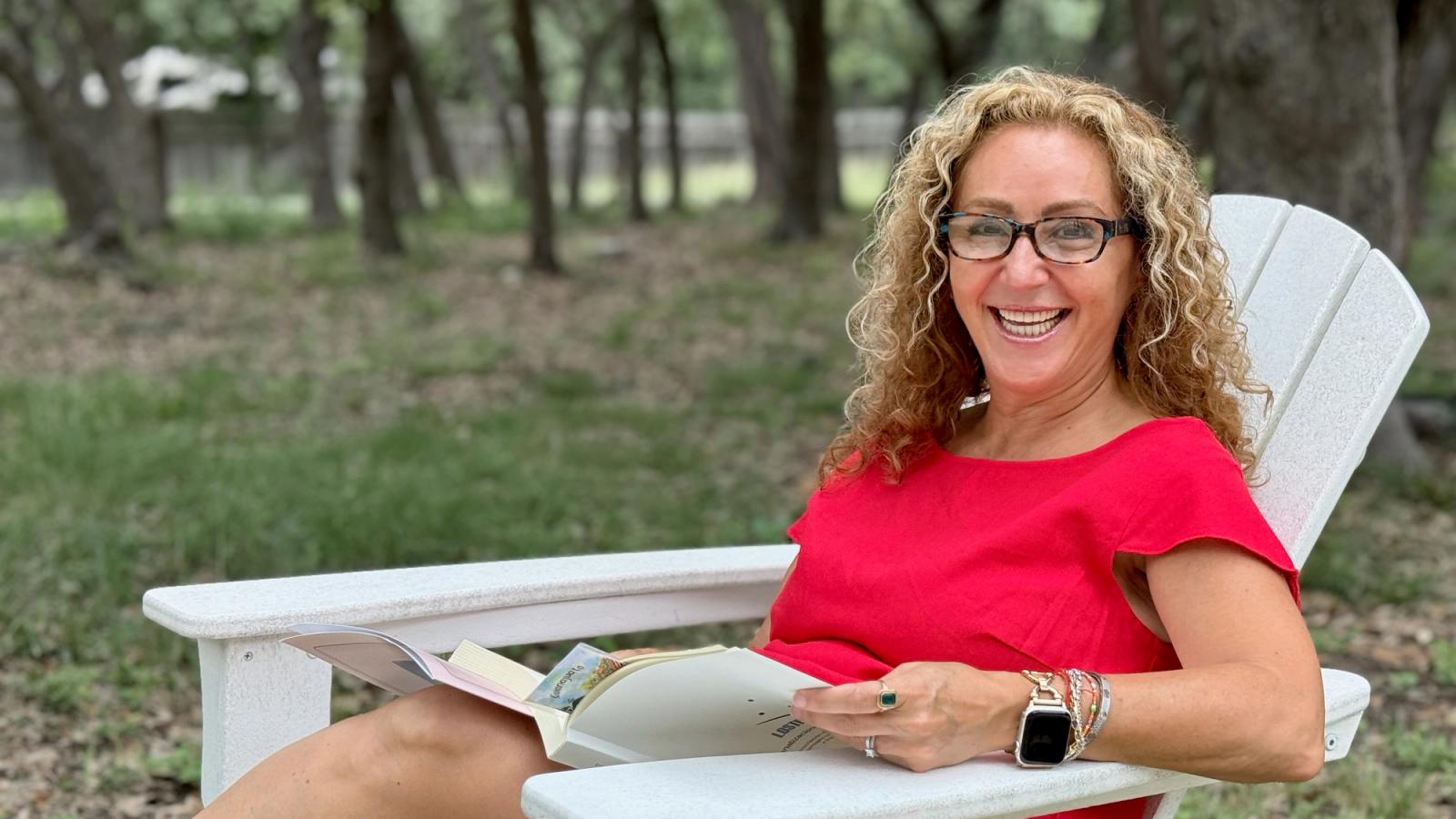 Claudia smiling on a porch with a cup of coffee