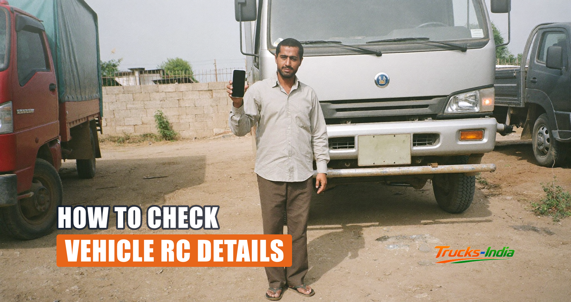 Person checking a vehicle registration record on a phone beside a parked Indian truck