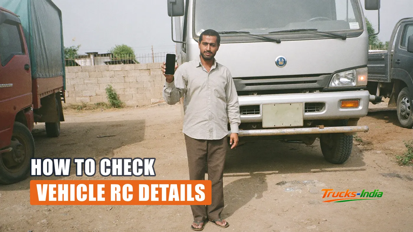 Person checking a vehicle registration record on a phone beside a parked Indian truck