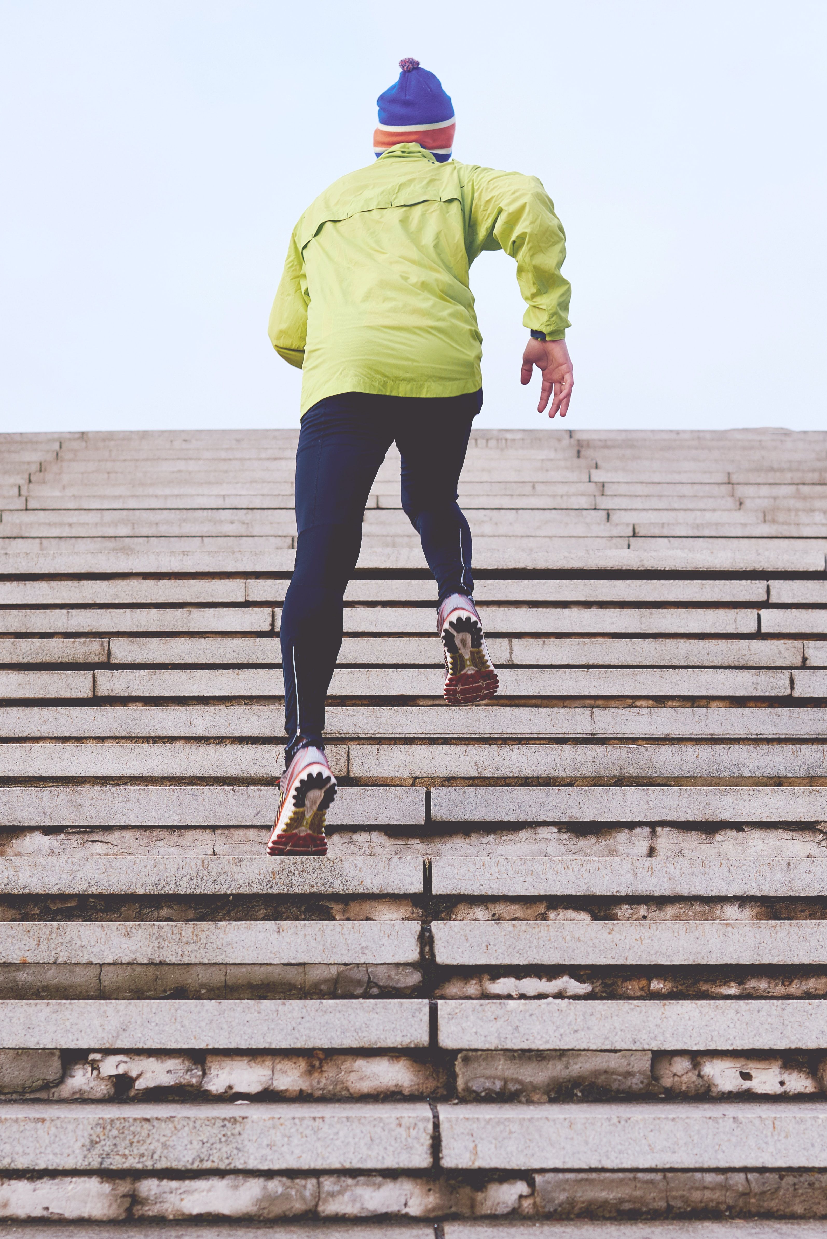 man running in green jacket and blue hat