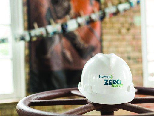 Koppers Zero Harm hard hat resting on a ship’s wheel