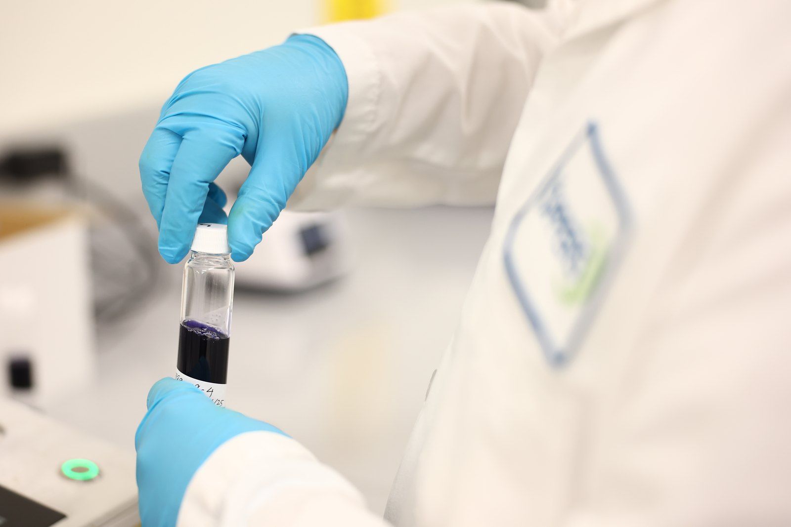 Gloved analyst holding a sample vial