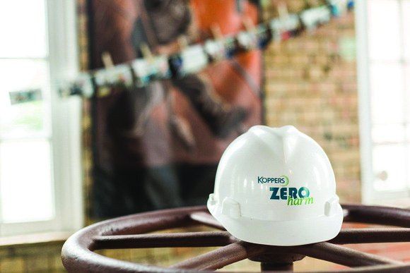 Koppers Zero Harm hard hat resting on a ship’s wheel