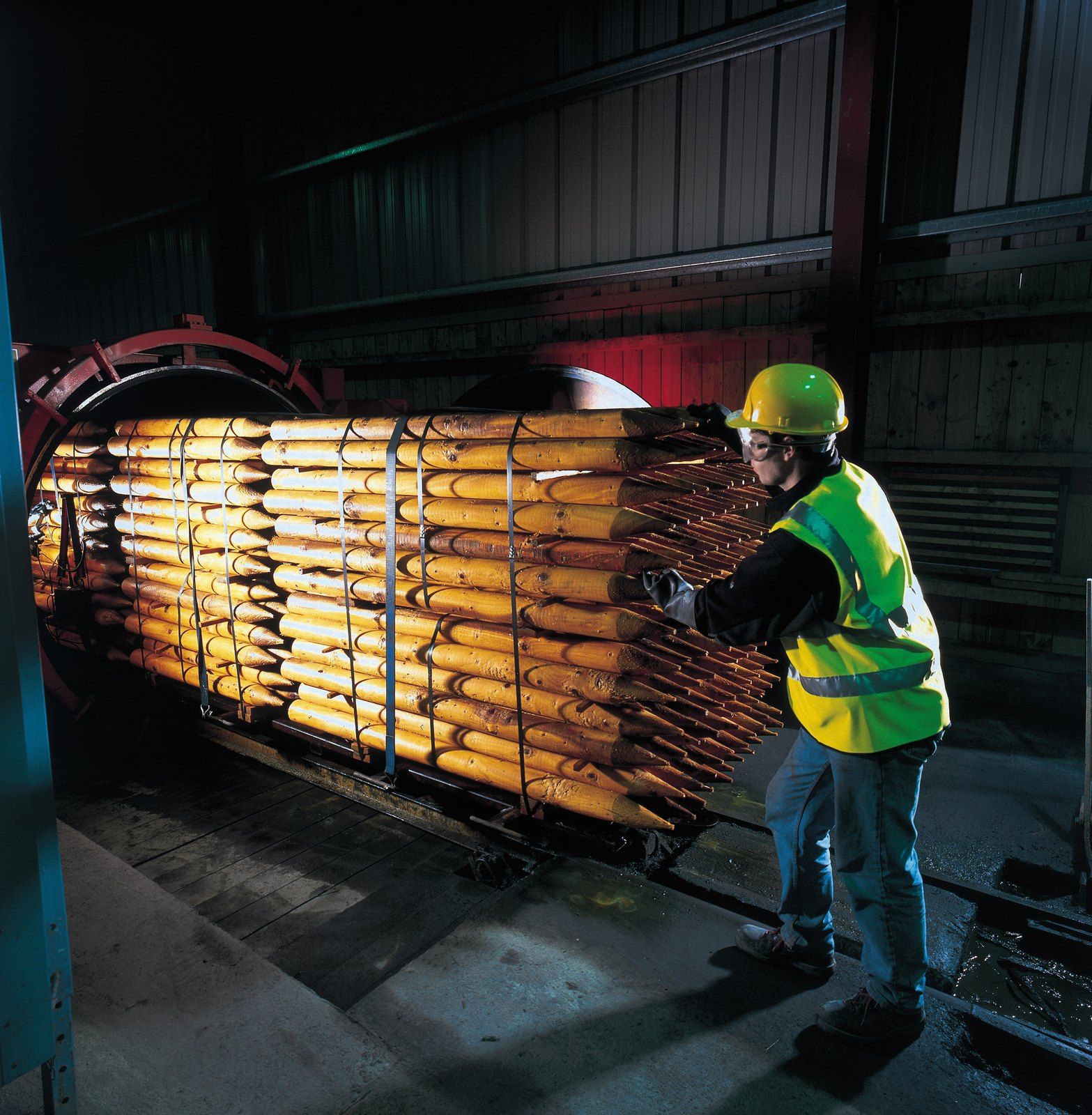 Operator loading a tram of posts into a treatment cylinder