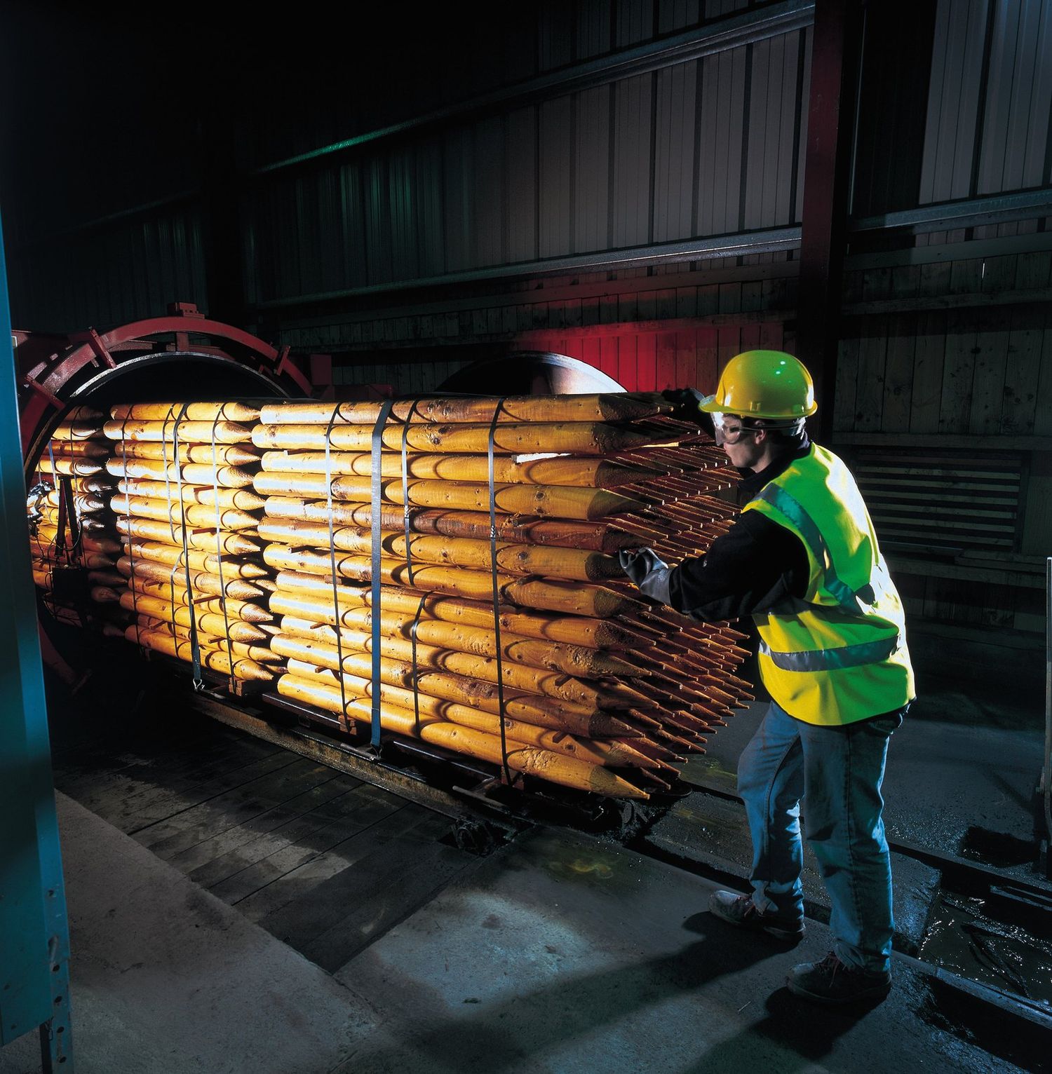 Operator loading a tram of posts into a treatment cylinder