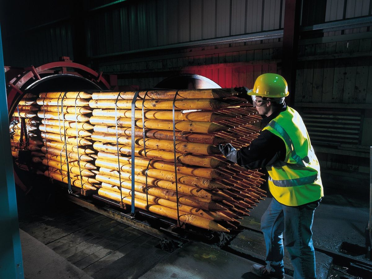 Operator loading a tram of posts into a treatment cylinder