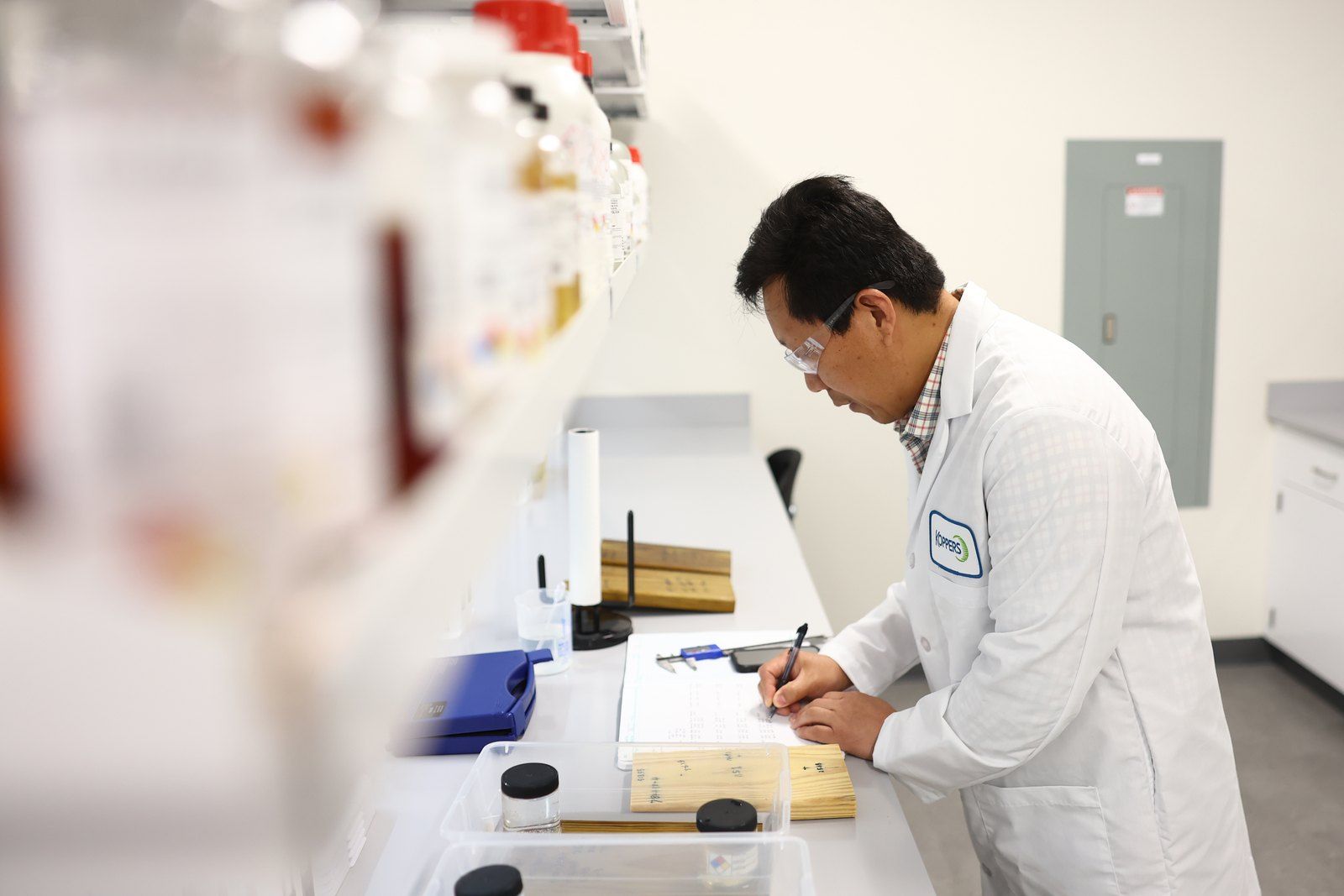 Analyst measuring a treated wood sample with calipers
