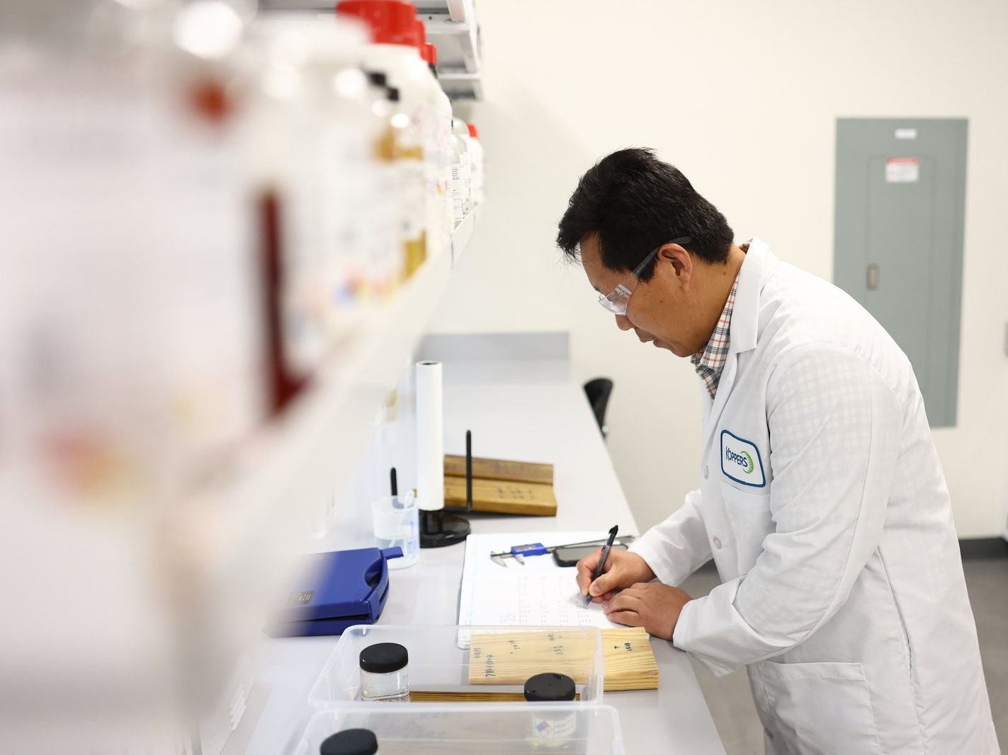 Analyst measuring a treated wood sample with calipers