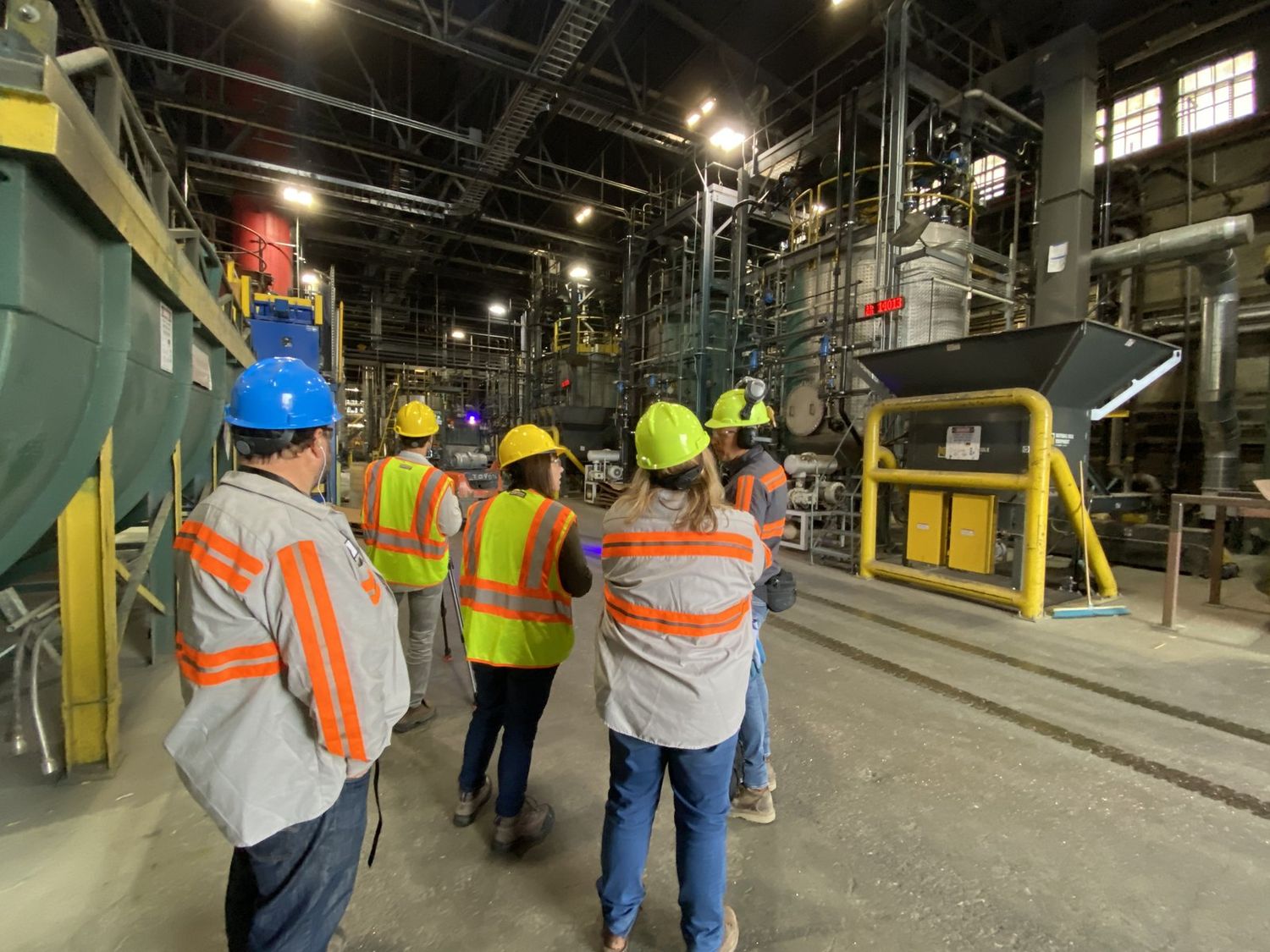 Visitors in hard hats touring the plant interior