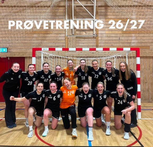 Et lag med smilende håndballspillere i svarte og oransje drakter poserer samlet foran et håndballmål i en idrettshall, med teksten «PRØVETRENING 26/27» skrevet øverst i bildet.