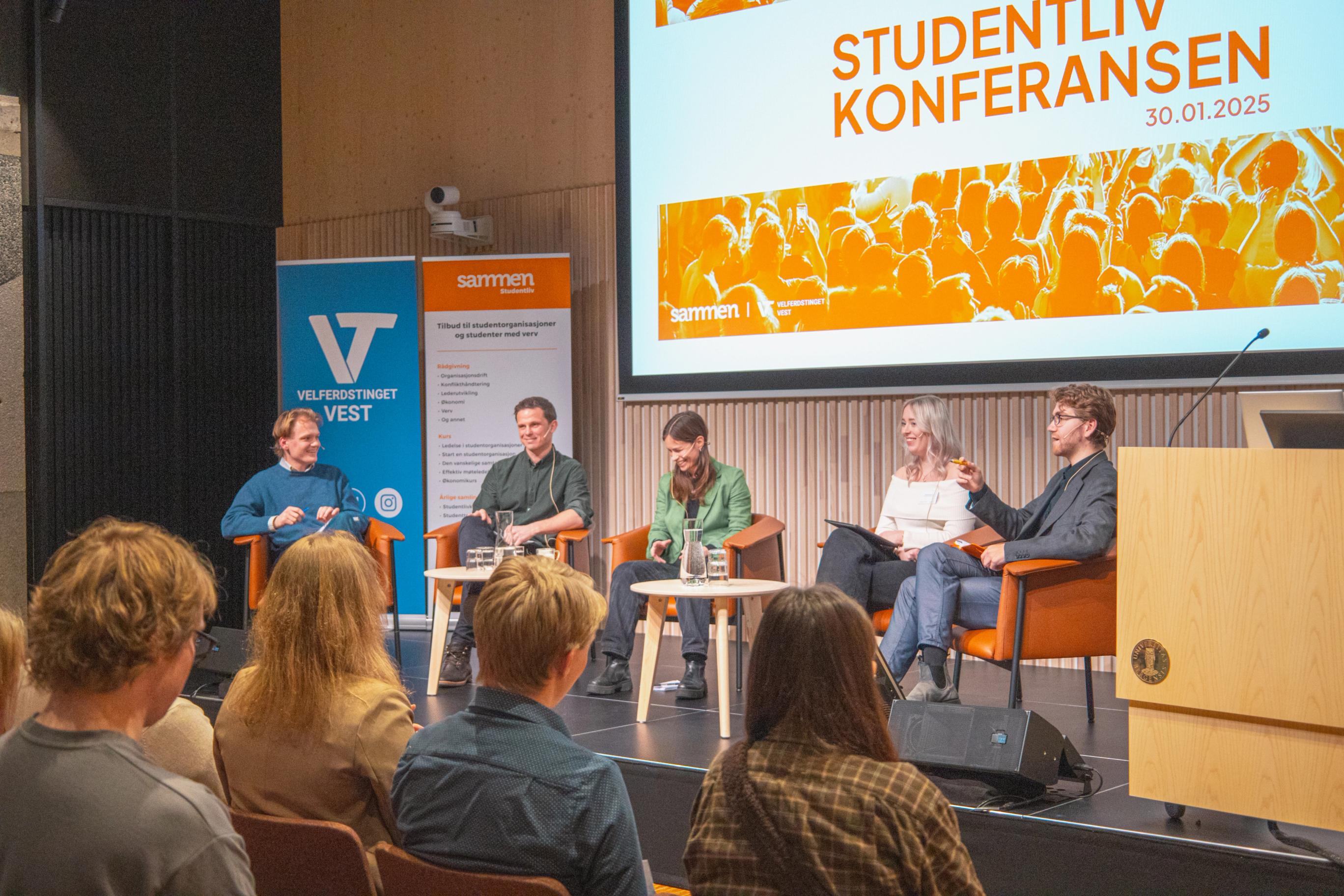 Paneldeltakere sitter på en scene foran et publikum under Studentlivkonferansen 30.01.2025, med store bannere fra Velferdstinget Vest og Sammen i bakgrunnen.