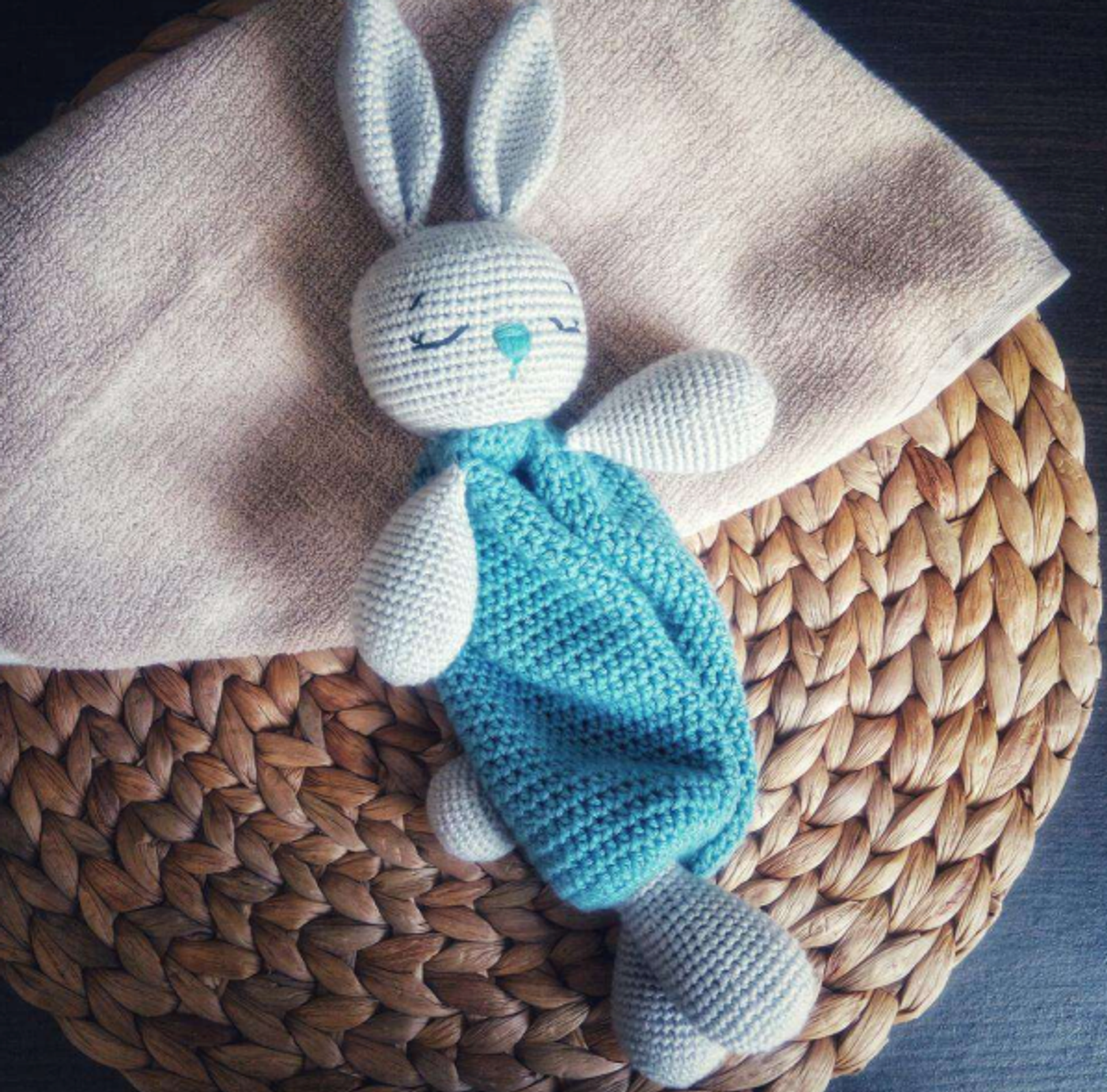 A handmade gray amigurumi bunny head attached to a teal blue crochet security blanket body, a free pattern for baby gifts.