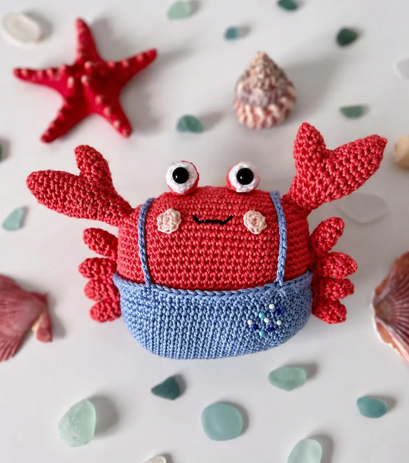 A cute orange amigurumi crab wearing blue overalls, handmade using this free crochet pattern.