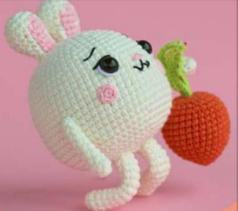 A cute, round, white crocheted chubby bunny holding a large orange carrot - Free Pattern
