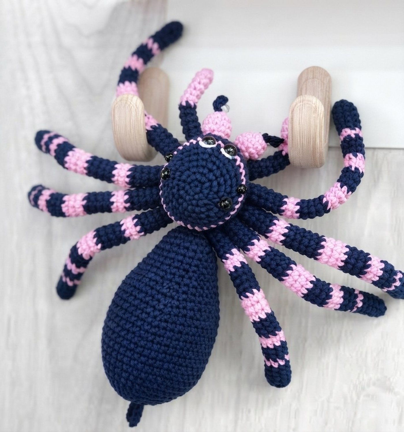Free crochet spider pattern: navy and pink striped amigurumi tarantula with eight posable legs, pink chelicerae and pedipalps, and black bead eyes