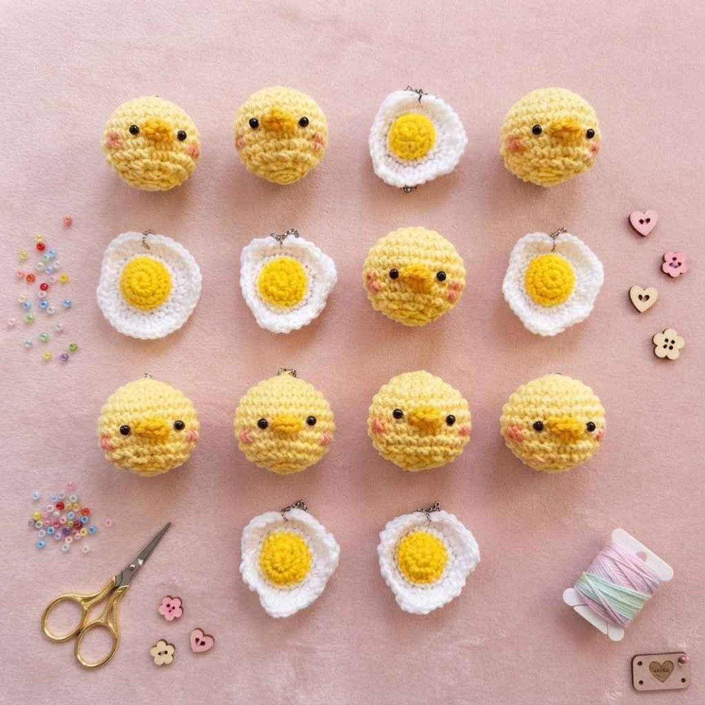 Small round yellow crochet baby chick with two black eyes, a little orange beak in the middle of its face and soft pink cheeks.