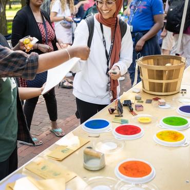 A woman in a shayla at a table with different colored stamps