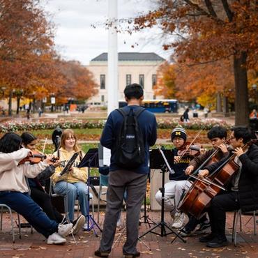 an orchestra outdoors plays on a variety of instruments